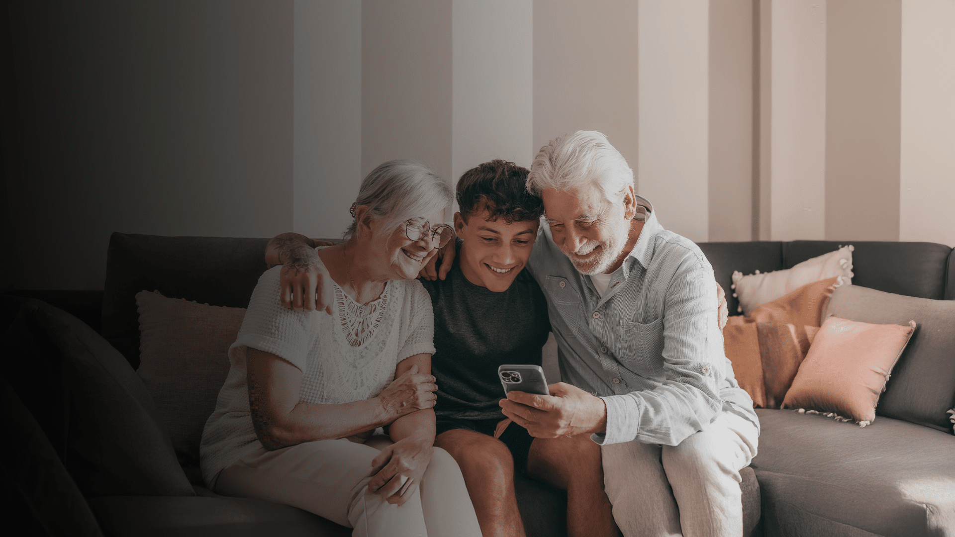 Família reunida no sofá olhando o celular, sorrindo